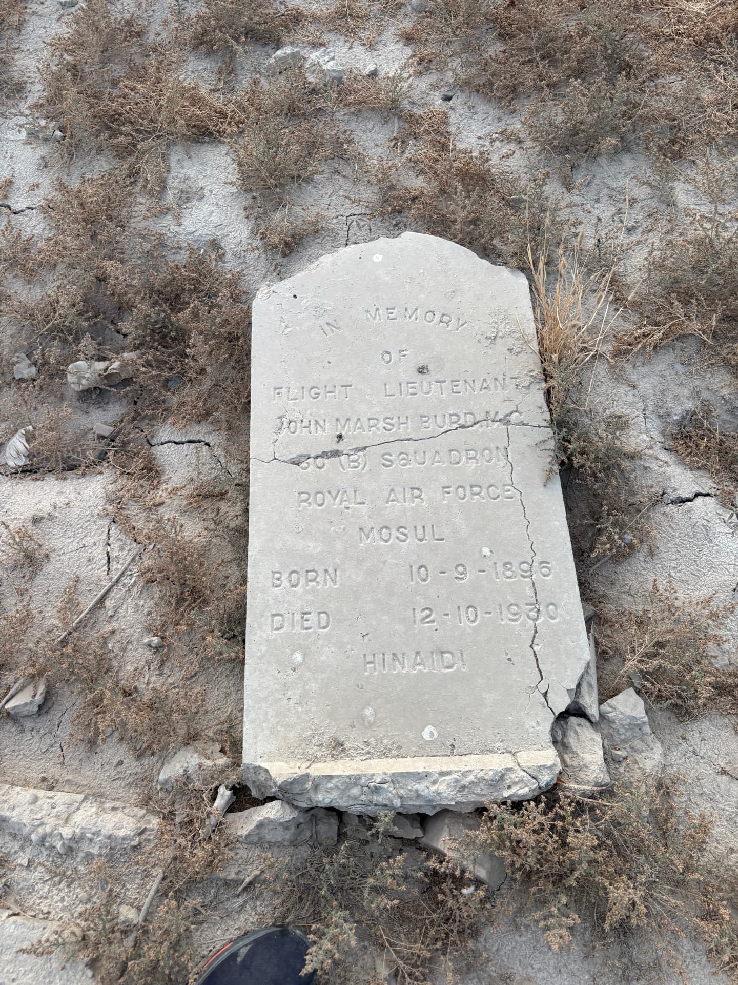 Flight Lieutenant John Marsh Burd MC, 30 (B) Squadron, Royal Air Force, Mosul, born 10 September 1896, died 12 October 1930, Hinaidi. The headstone lies broken on cracked ground.