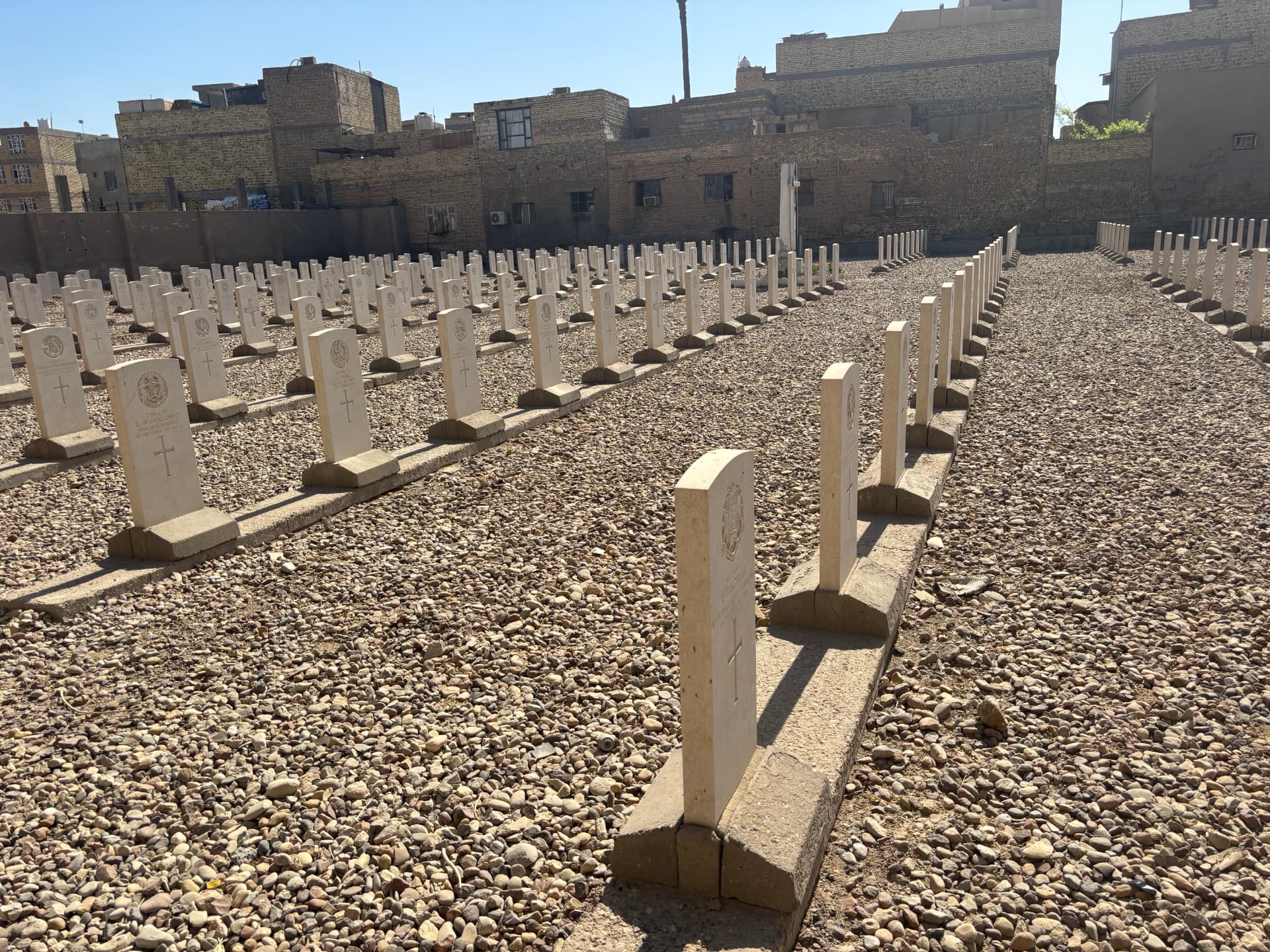 A wider view across the cemetery showing the rows of headstones and, to the right, the blank uninscribed markers set over graves that could not be identified.