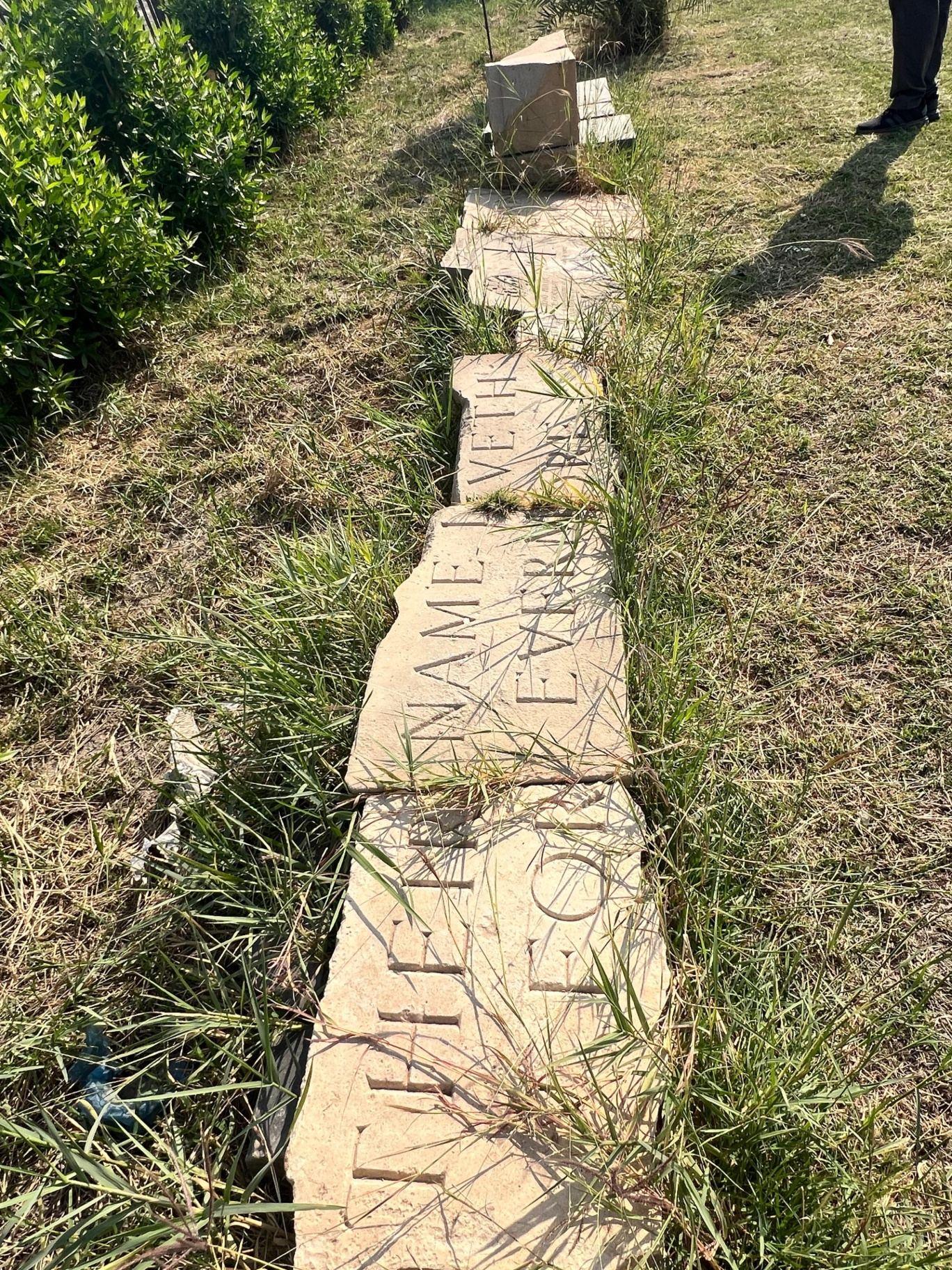 The remains of the Stone today, broken into fragments and lying in the grass at the site. The carved inscription "THEIR NAME LIVETH FOR EVERMORE" is still partially legible across the shattered pieces.