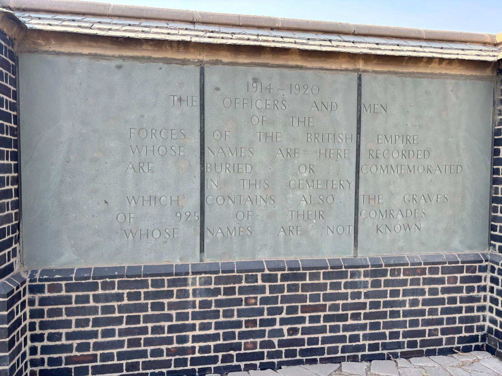 The dedication panel on the Memorial Wall, recording the officers and men of the Forces of the British Empire buried or commemorated in the cemetery, 1914-1920, together with the 925 of their comrades whose names are not known.