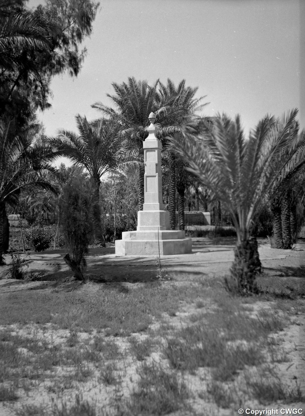 The Indian Forces Memorial standing among date palms within the cemetery enclosure, photographed in its early years when the grounds were tended as a garden. © CWGC.