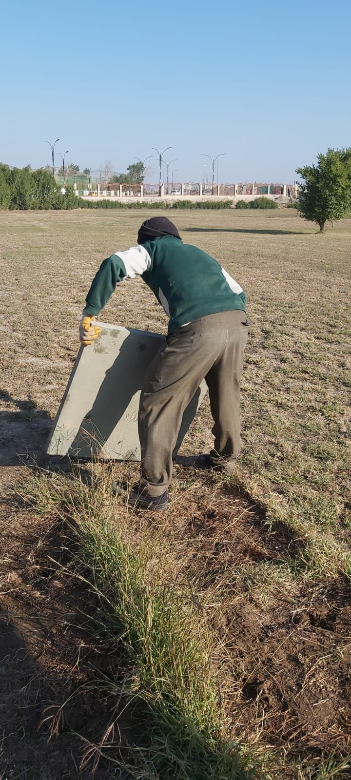 A worker carrying one of the heavy memorial panels across the cemetery grounds during the 2022 renovation.