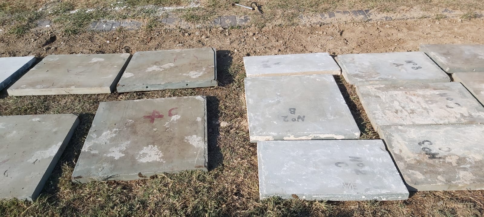 Memorial panels laid out on the grass, marked and numbered (No.2, No.3, etc.) ready for re-installation in their correct positions on the wall.