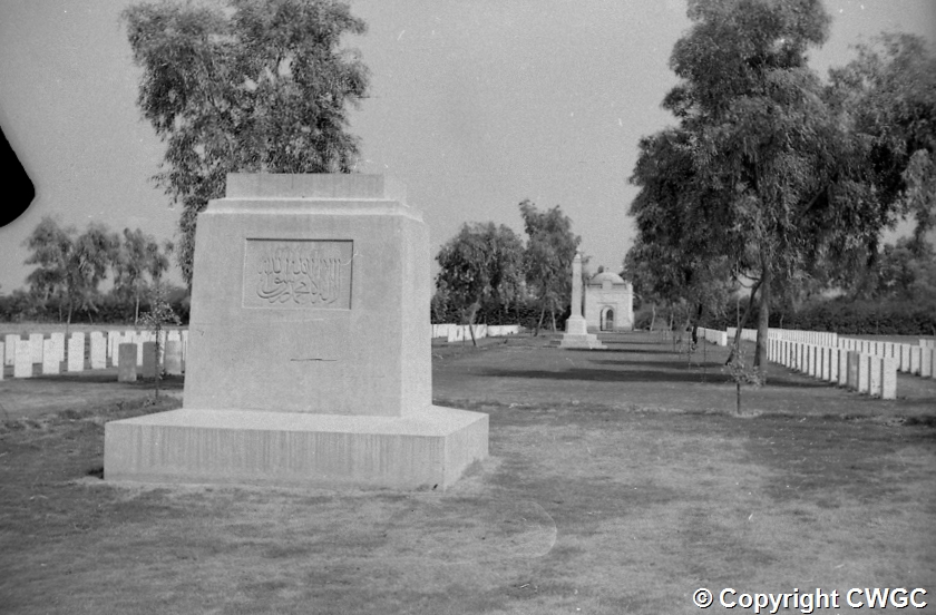 The inscribed pedestal in the foreground, with the Cremation Memorial visible in the middle distance among the trees and rows of headstones. © CWGC.