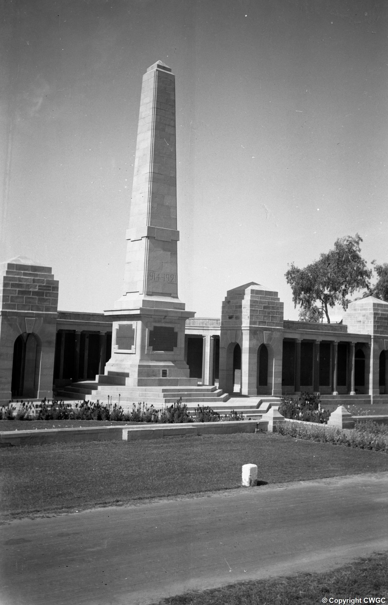 The central obelisk inscribed 1914-1921, photographed in 1957, with the flanking pavilions and colonnaded screen wall behind. © CWGC.