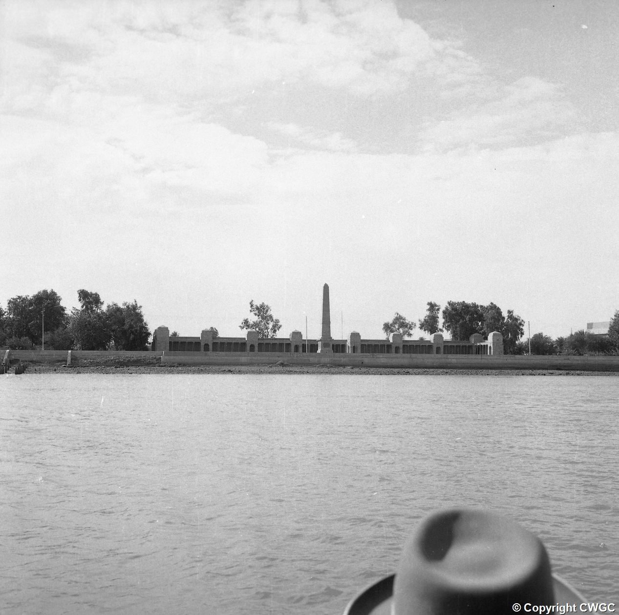 The Basra Memorial in its original position on the bank of the Shatt al-Arab, the full sweep of the colonnaded screen wall and central obelisk seen from across the water. © CWGC.