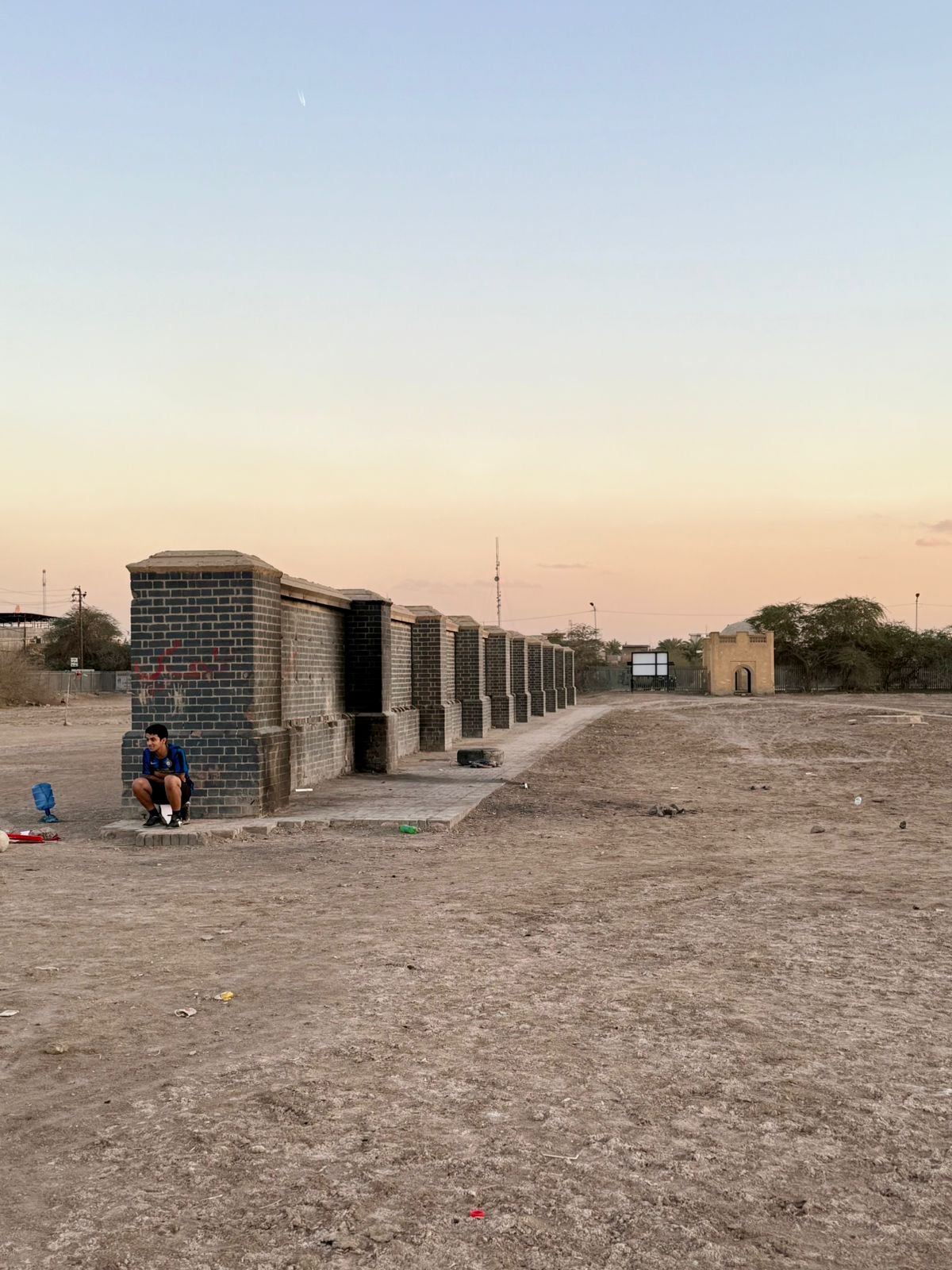 The Memorial Wall today, its inscribed panels removed and the bare brick piers and recesses left exposed, with one of the gatehouses visible at the far end. Photo: Shane Potaka.