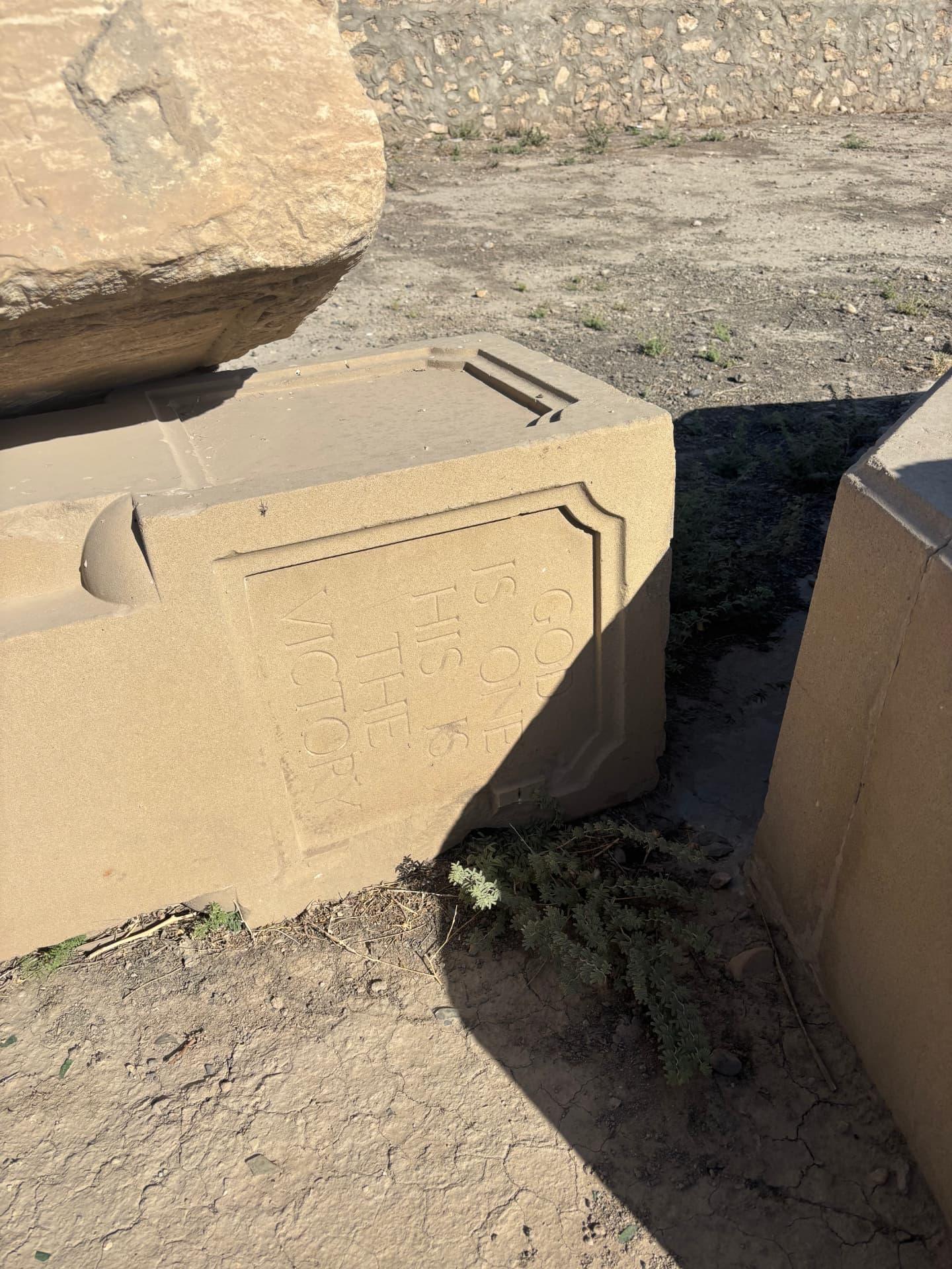 A block from the Muslim memorial carrying the inscription "God is one, His is the victory", tipped on its side among the other dismantled stones.