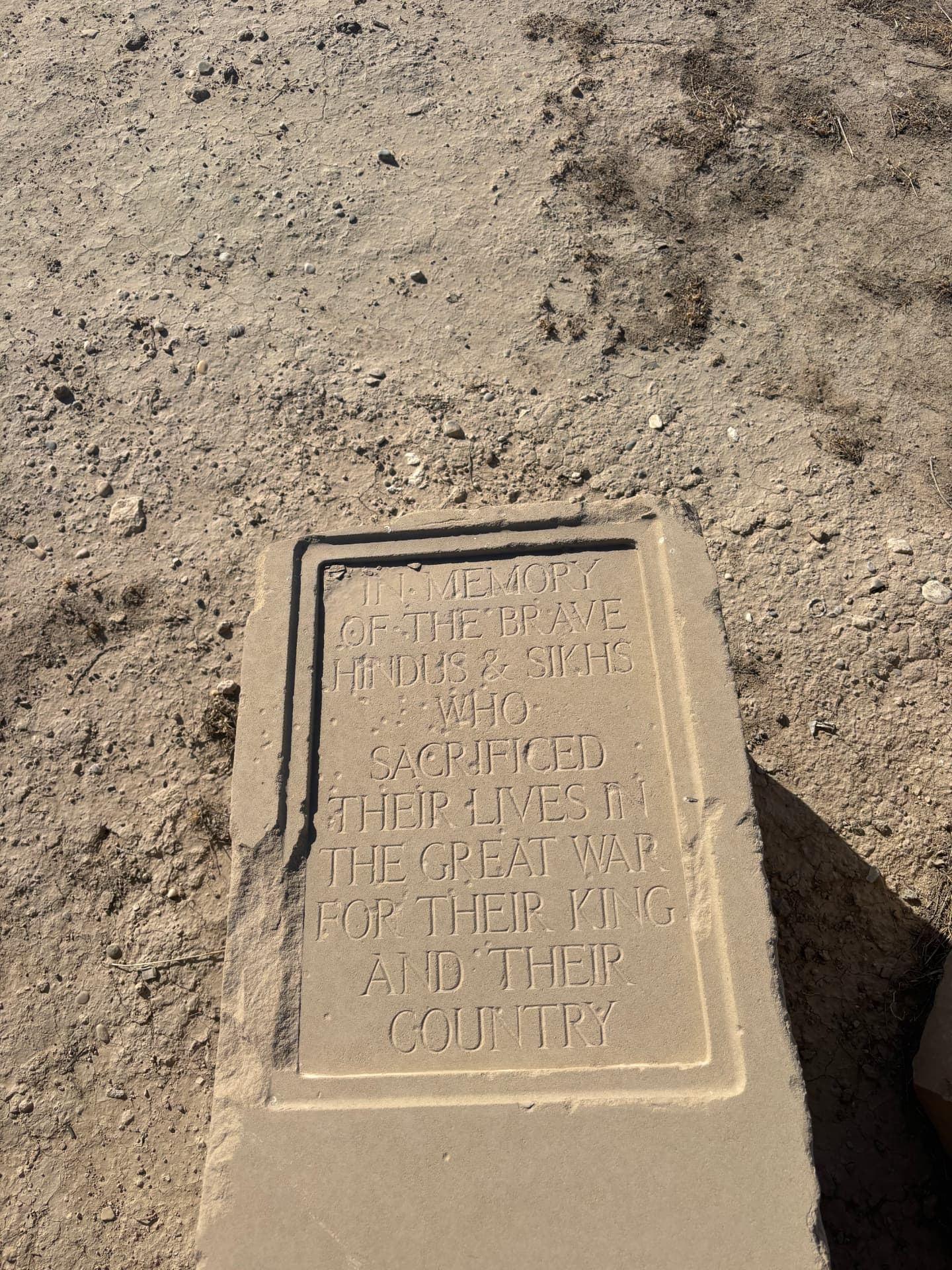 The panel reading "In memory of the brave Hindus and Sikhs who sacrificed their lives in the Great War for their King and their Country", face up in the dust.