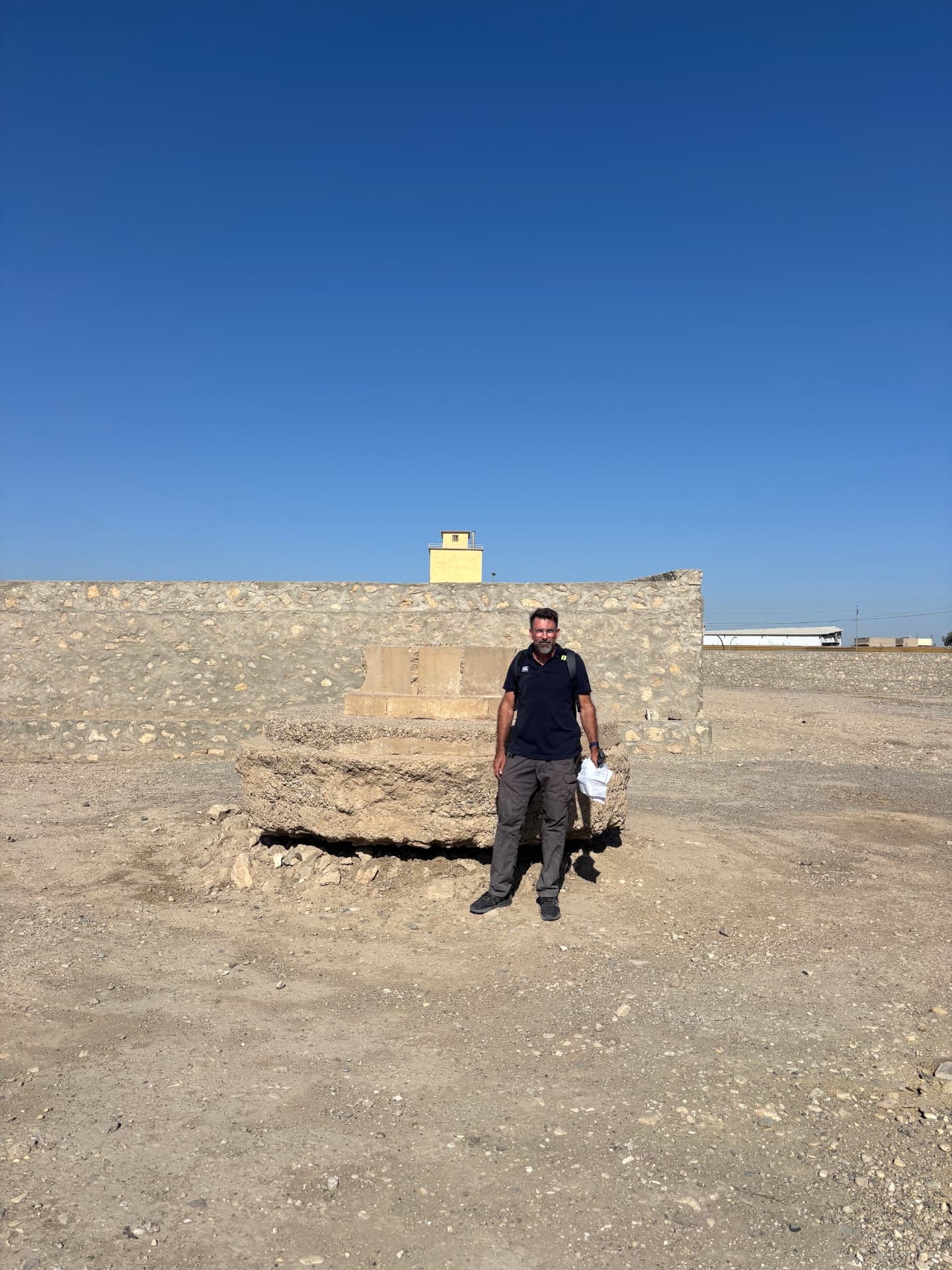 The base of the Cross of Sacrifice, with a six foot person for scale, showing the ground cut away to expose the pedestal below the level of its foundation.