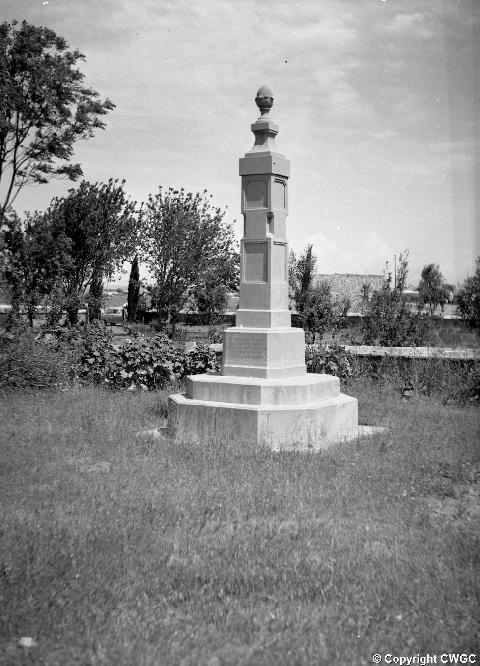 One of the Indian memorial obelisks standing on its stepped base in the grass, with inscription panels on each face. © CWGC.