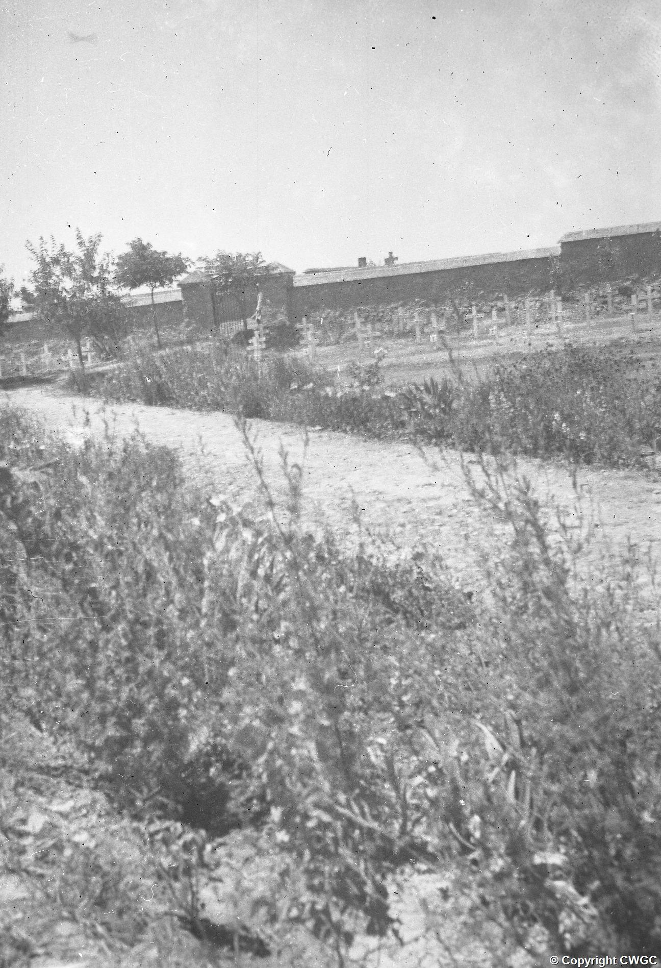 An early view across the cemetery towards the entrance, showing temporary grave crosses and young planting. © CWGC.
