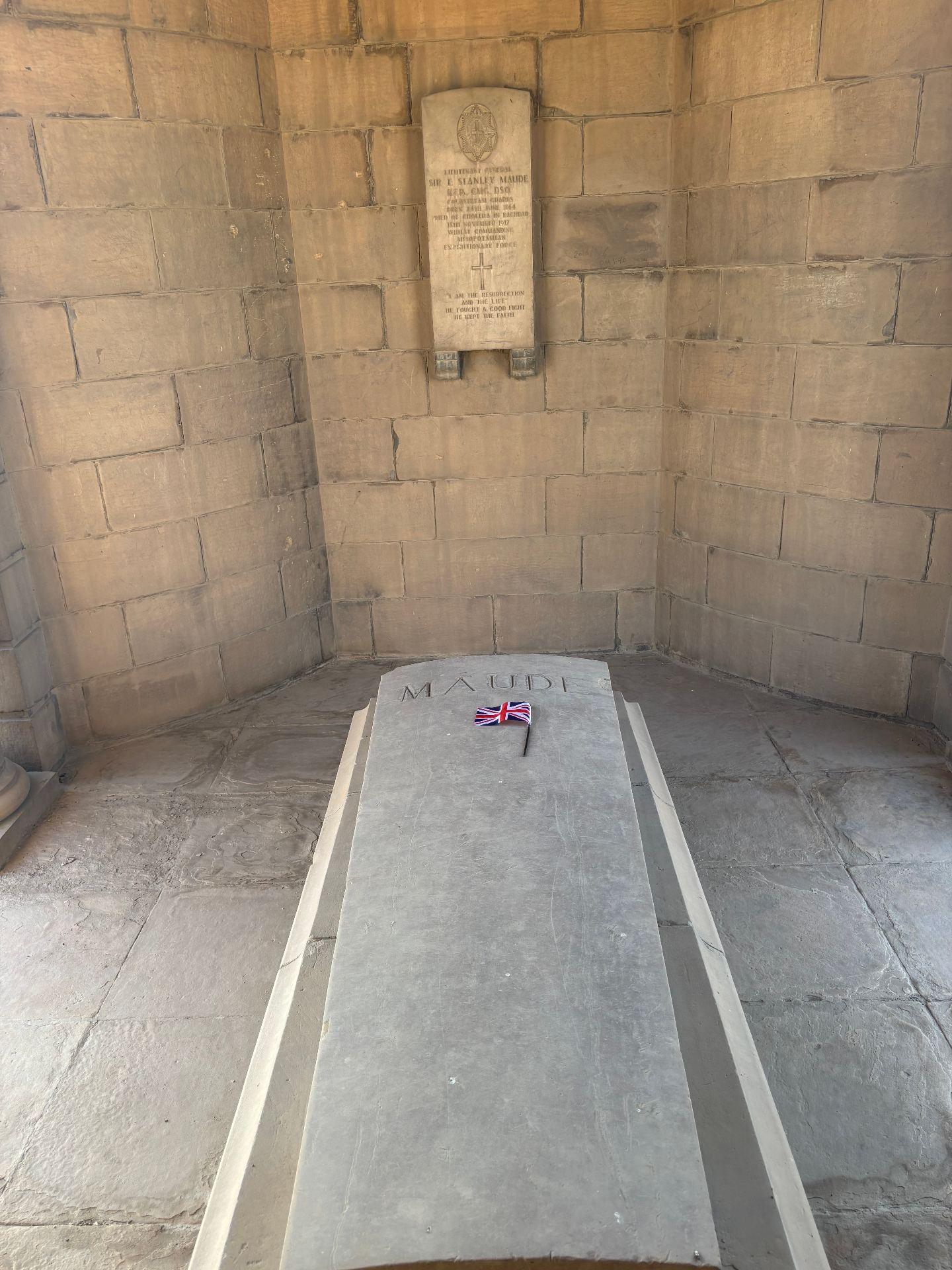 Interior of the tomb showing General Maude's grave slab inscribed 'MAUDE', with a small Union flag laid on top, and the wall plaque above commemorating Lieutenant General Sir F. Stanley Maude, K.C.B., C.M.G., D.S.O., born 24th June 1864, died of cholera in Baghdad 18th November 1917 while commanding the Mesopotamian Expeditionary Force: 'I am the Resurrection and the Life. He fought a good fight, he kept the faith.'